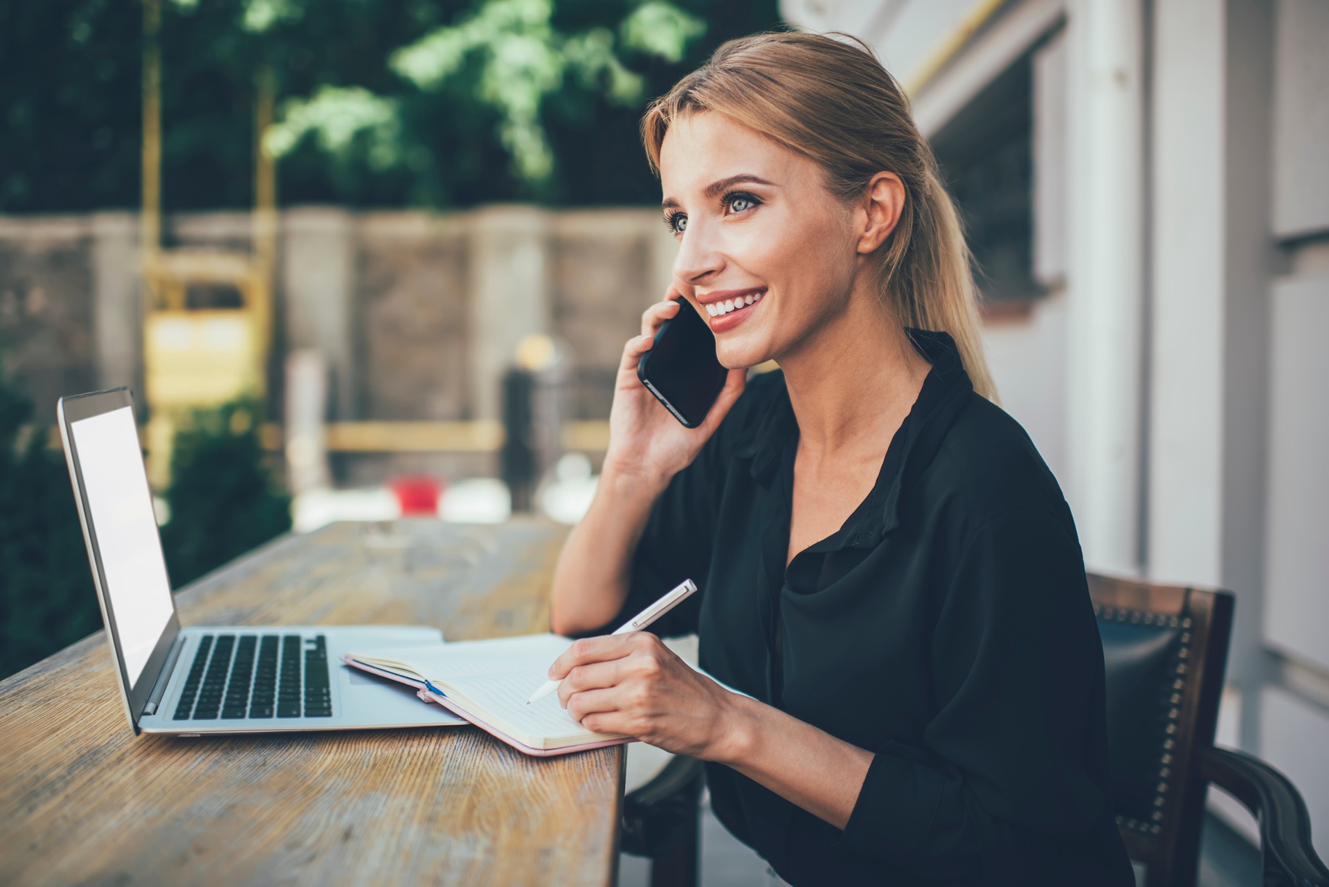 Woman taking notes while on the phone.