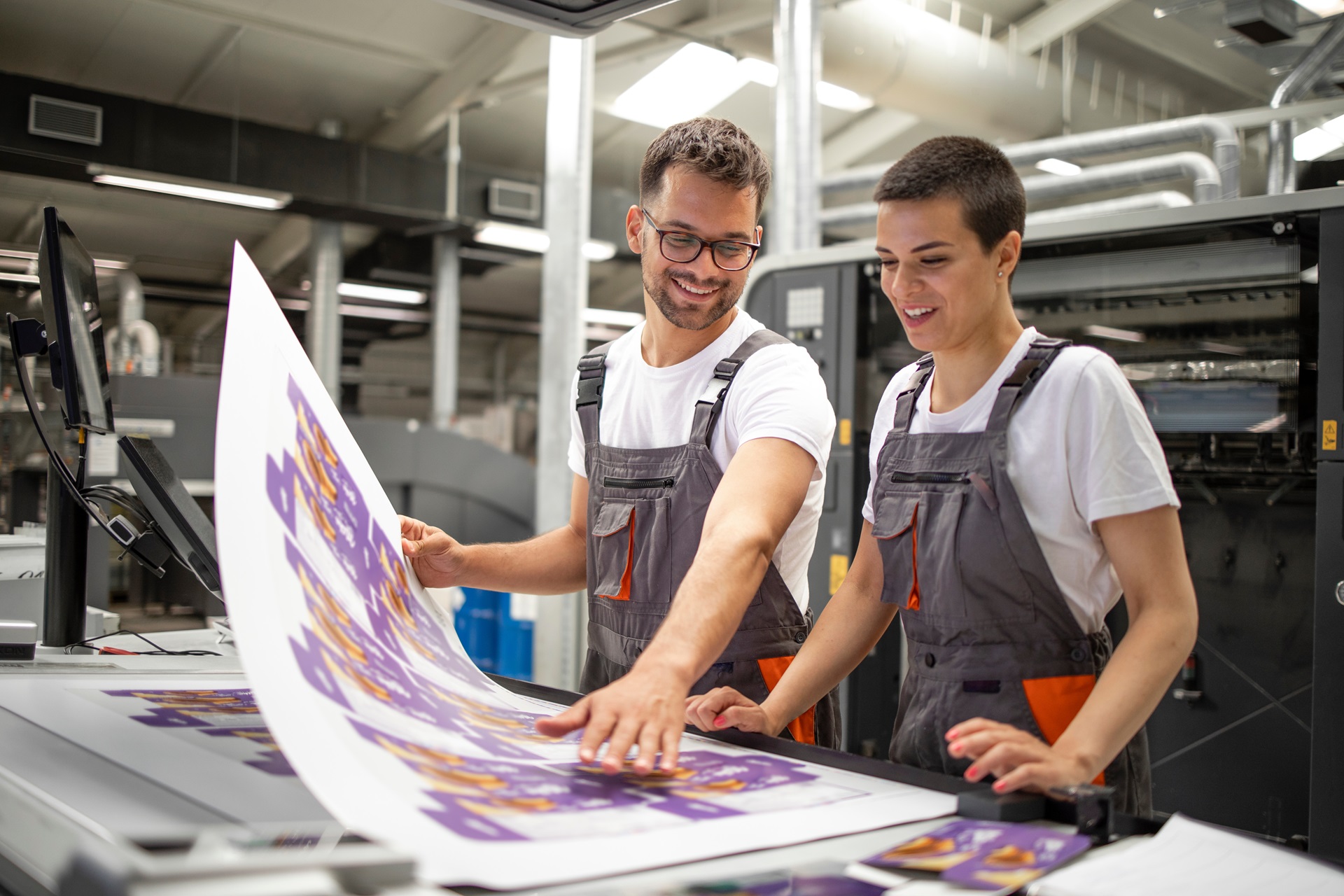 Two printing employees reviewing printed material.