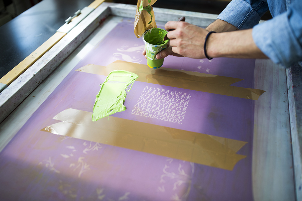 A person applying ink to a silkscreen to be printed.